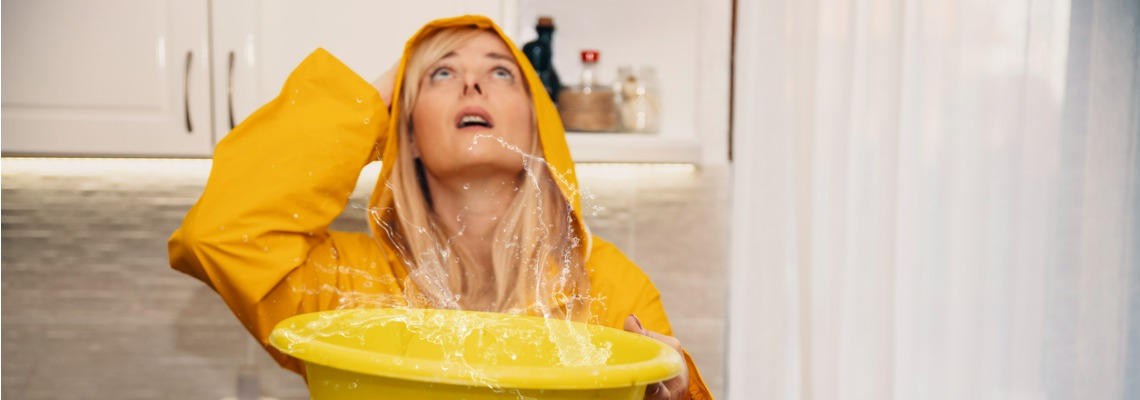 woman collecting water leaking from ceiling