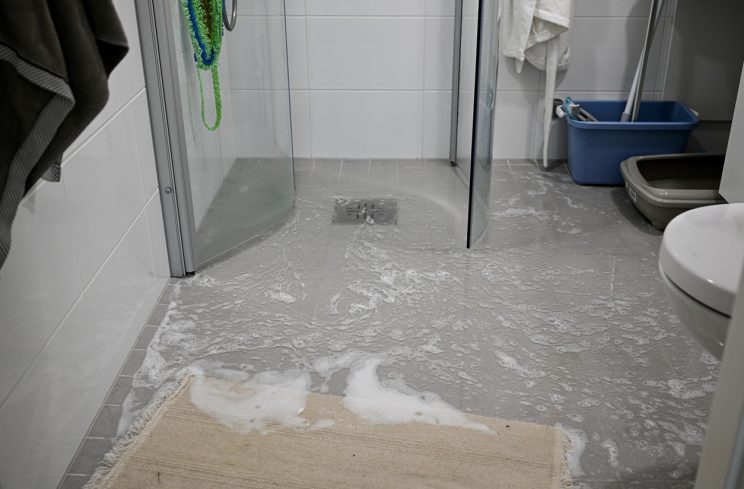 a tiled shower flooded with excess leaking water