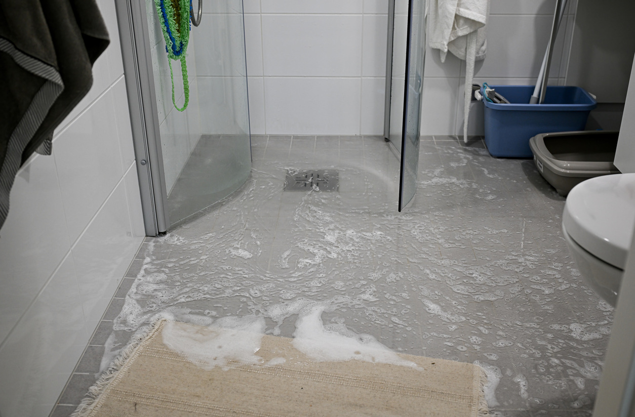 a tiled shower flooded with excess leaking water